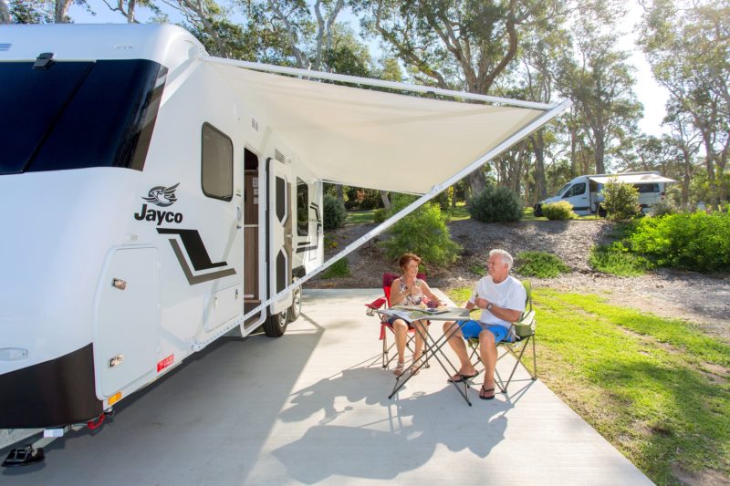 Cement slab powered site with caravan and seniors at BIG4 Sawtell Beach Holiday Park, surrounded by beautiful trees